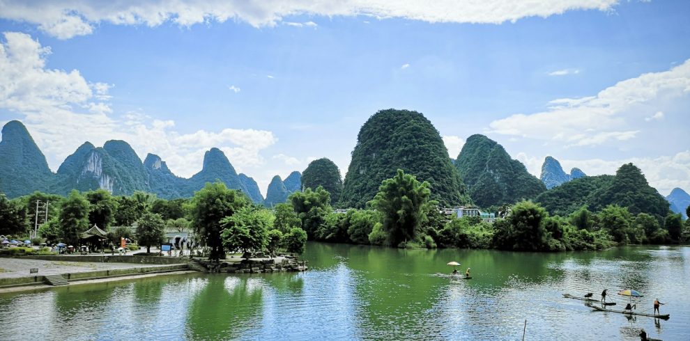 green trees near lake under blue sky during daytime